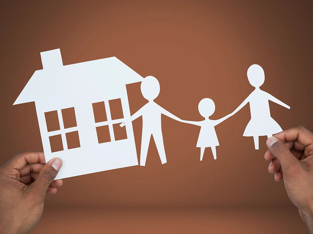 Hands holding paper house and family cut-outs
