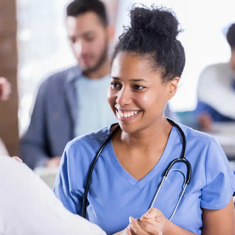 A female physician smiling with a stethoscope around her neck
