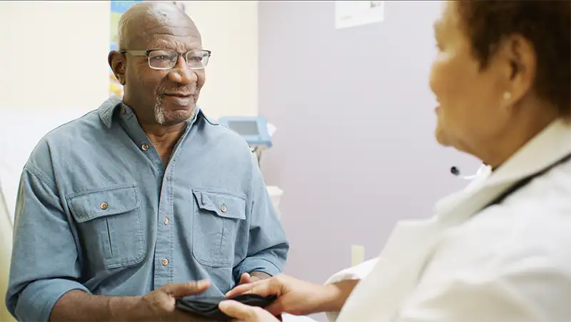 An African American man sitting in a doctors office while his physician talks to him